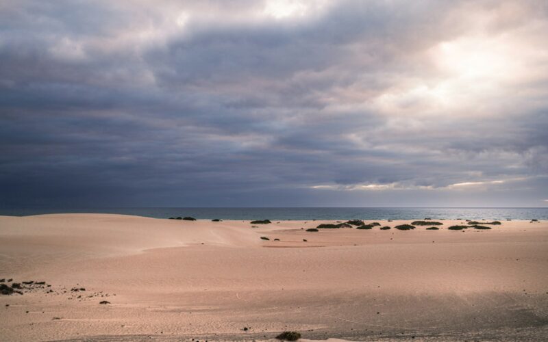 Witte zandduinen van Corralejo met de zee erachter
